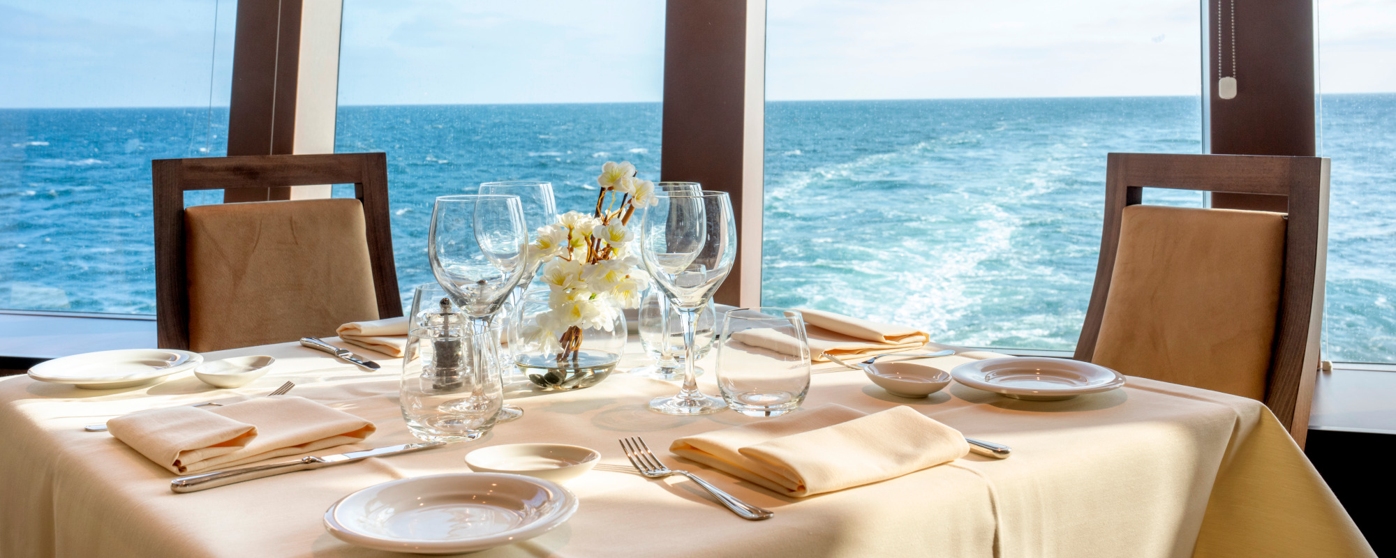 Blick auf gedeckten Tisch im Restaurant der MSC Euribia mit Ausblick auf blaues Meer