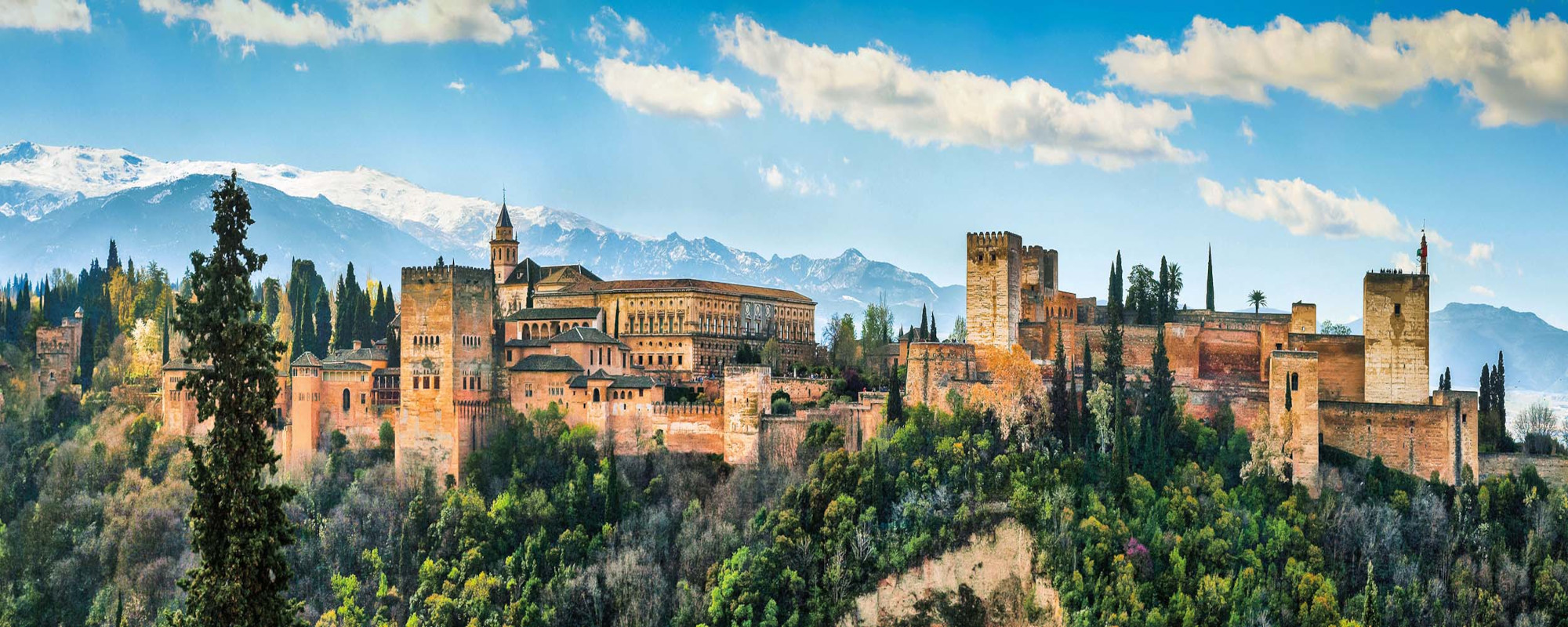 Spanien - Ausblick auf Alhambra mit Bergen im Hintergrund und Wald im Vordergrund