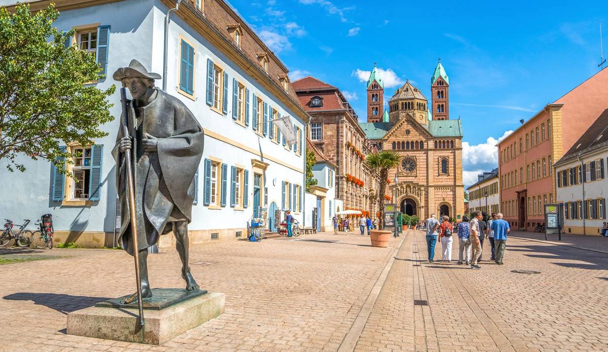 Blick auf Denkmal und Straße mit Gebäuden und Menschen unter blauem Himmel