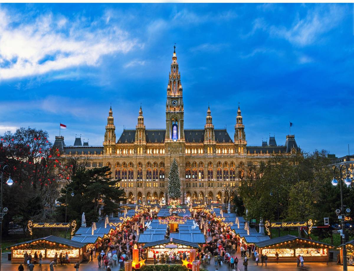 Aufnahme eines winterlichen Weihnachtsmarktes vor einem historischen Gebäude unter blauem Himmel