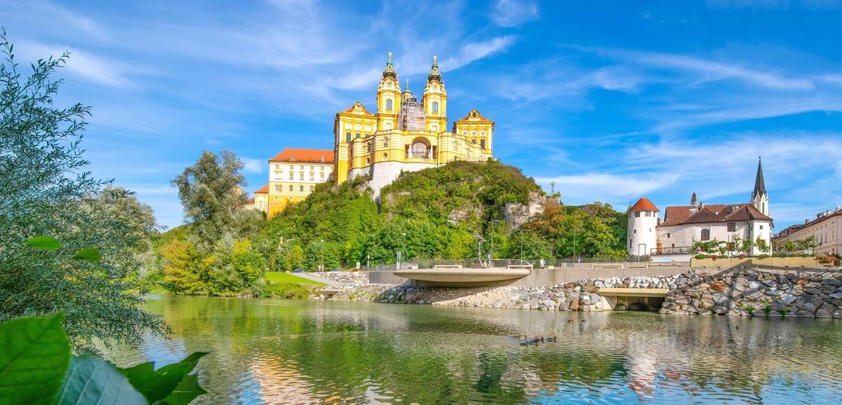 Blick auf Fluss und ein historisches Gebäude auf einem grünen Hügel