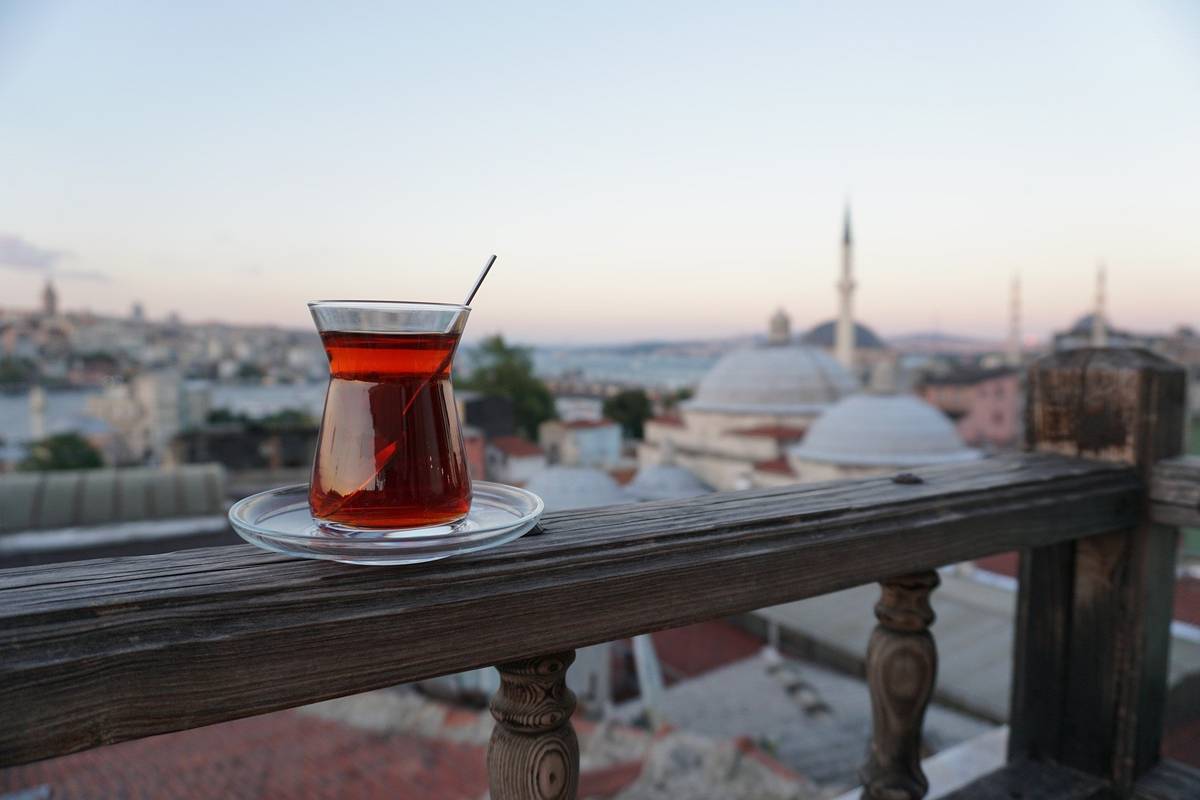 Aufnahme eines Glases mit Türkischem Tee auf einem Geländer mit Blick auf türkische Skyline