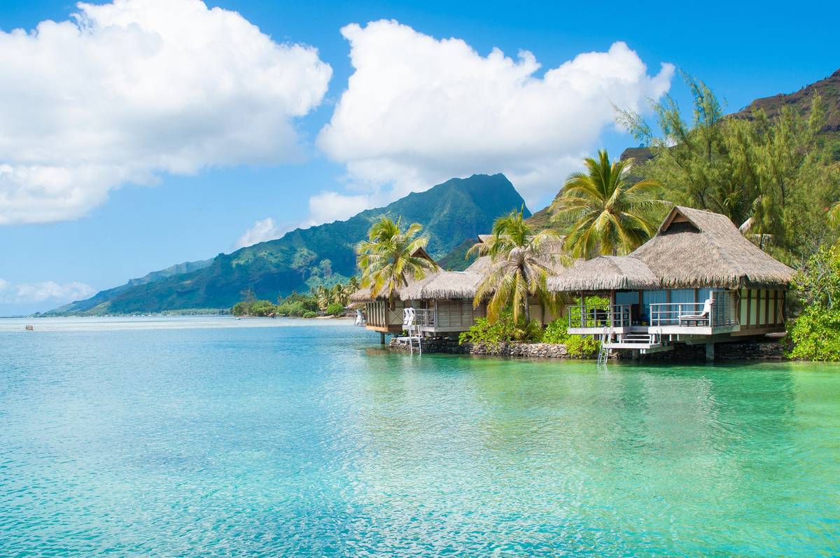 Blick auf Haus in Moorea auf Stelzen im kristallklaren blauen Wasser.