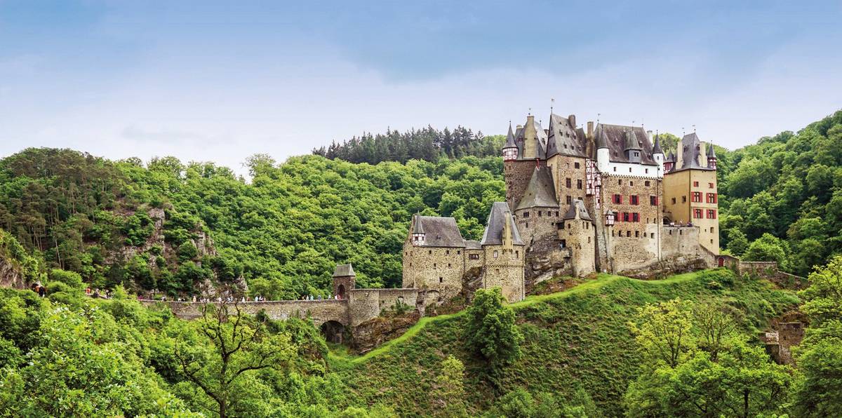 Aufnahme der historischen Burg Eltz an einem Hang mit grüner Landschaft in der Umgebung