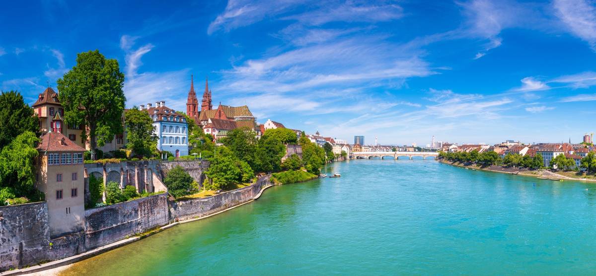 Blick auf türkisfarbenen Fluss mit historischer Stadt auf der linken Seite und Brücke im Hintergrund