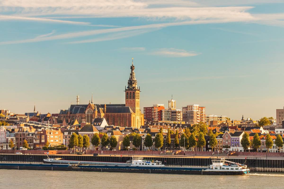Niederländische Stadt Nijmegen am Rhein bei Sonnenuntergang mit Schiff