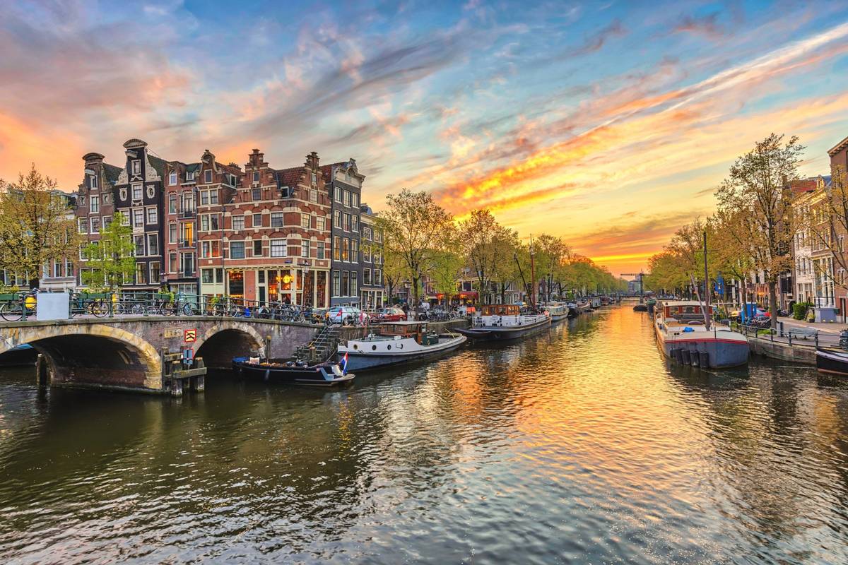 Ansicht auf Kanal mit anliegenden Booten. Historische Gebäude im Hintergrund bei Sonnenuntergang