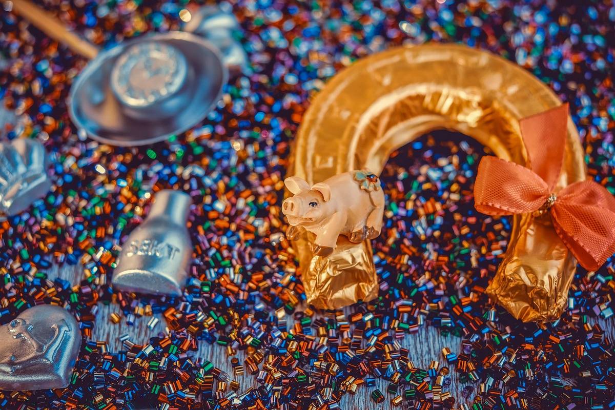 Goldenes Hufeisen und Glücksschwein als Nahaufnahme mit Glitter und typischen Gegenständen für Silvester