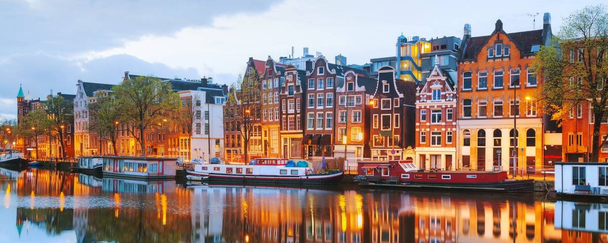 Blick auf historische Gebäude in Amsterdam an einer Gracht bei bewölktem Himmel