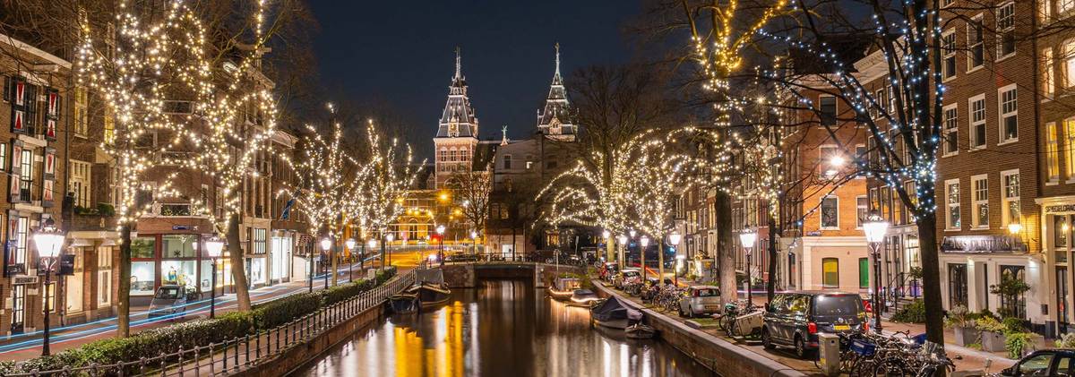 Abendlicher Lichterglanz über der Gracht in Amsterdam mit Spiegelung im Wasser