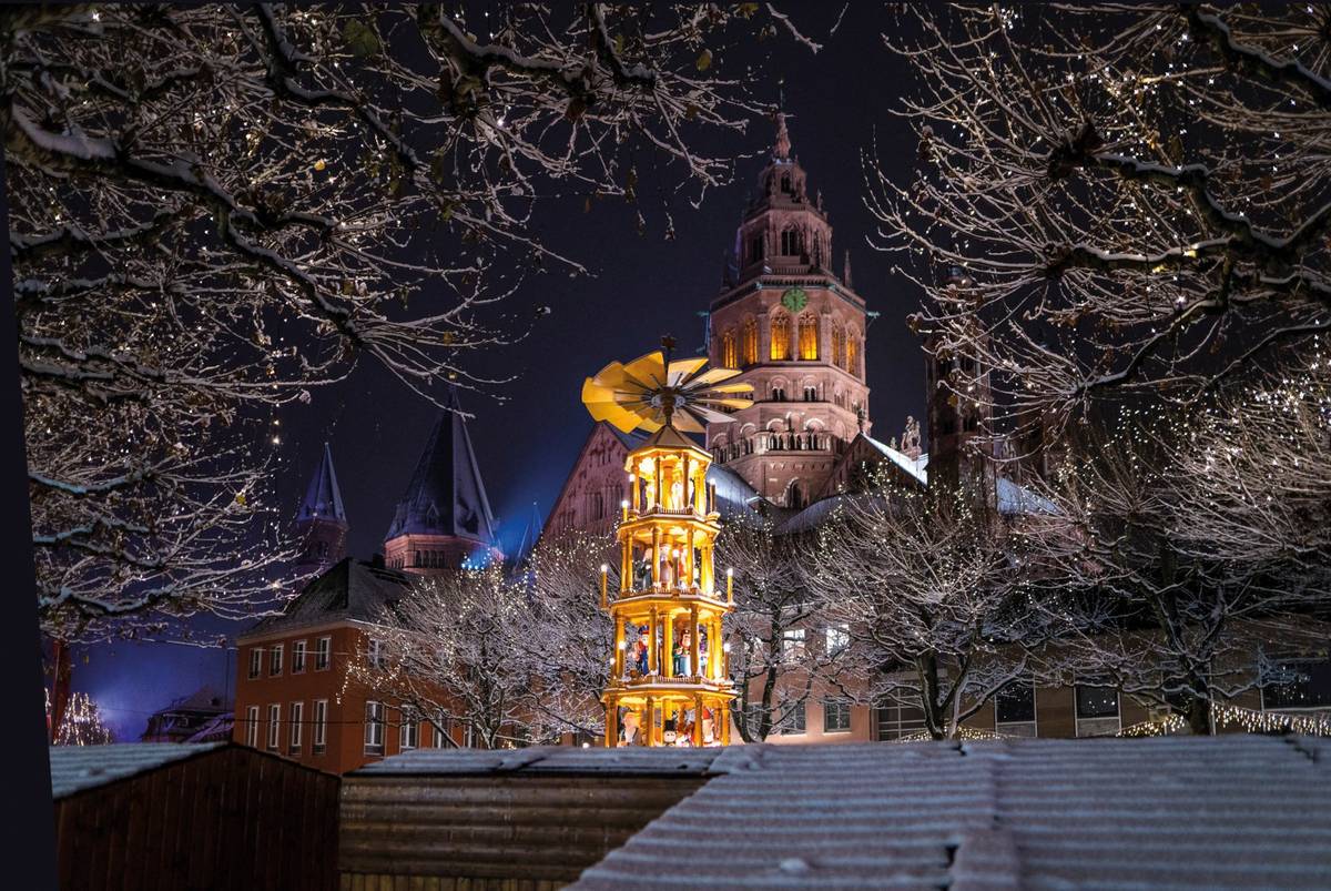Mainz bei Nacht mit weihnachtlichem Lichterturm und Figuren vor historischem Gebäude