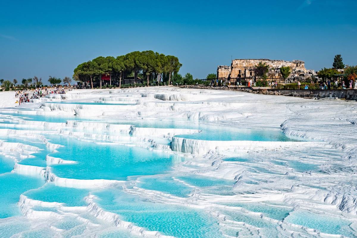 Weiße Becken mit türkisfarbenem Wasser, die durch kalkhaltige Thermalquellen zu Kalkterrassen geformt wurden in Pamukkale