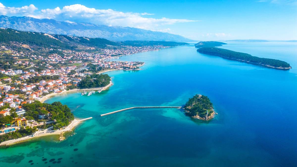 Drohnenbild von Rab in Kroatien mit malerischer Küste an türkisblauem Wasser und Stadtpanorama