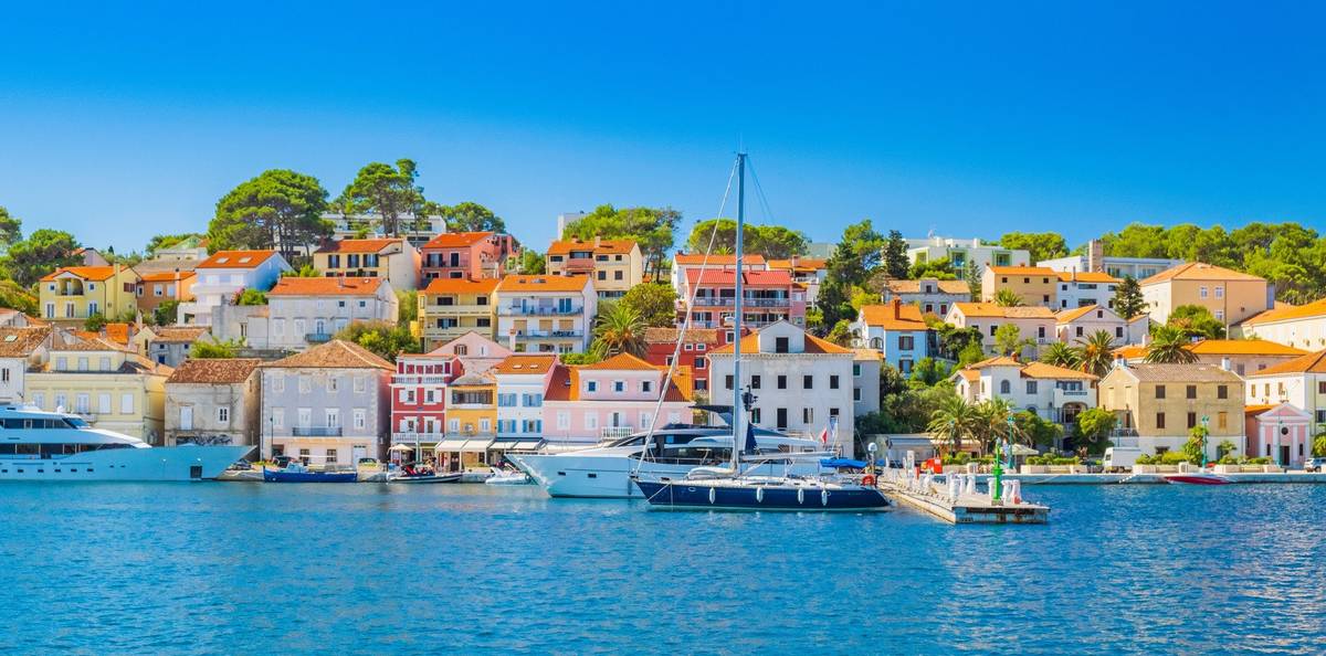 Szene von Mali Losinj an der blauen Adria. Kroatische Häuser mit orangefarbenen Dächern zeigen atmosphärisch die Schönheit von Küstenkreuzfahrten