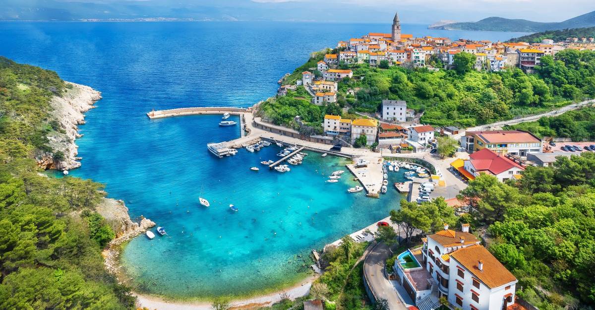 Das Dorf Vrbenik auf der Insel Krk in Kroatien als Luftaufnahme. Blaues Meer erstreckt sich über Horizont.