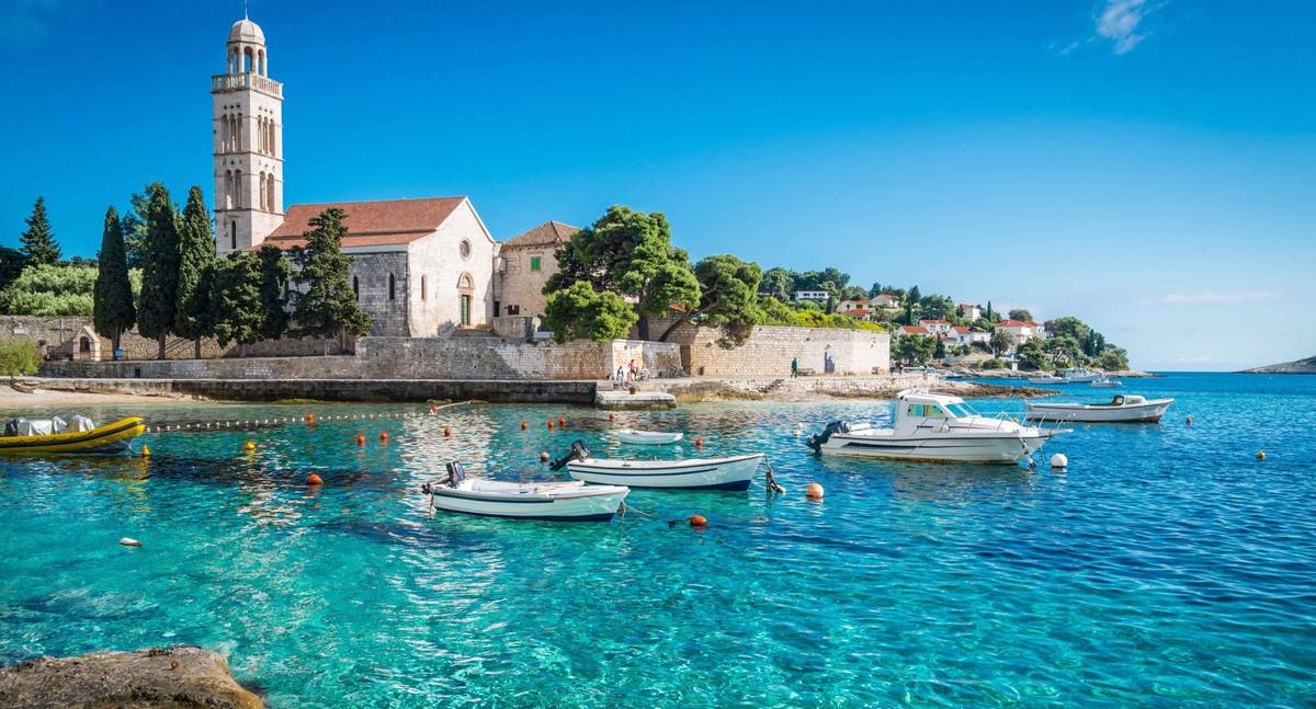 Blick auf Anleger bei der Insel Hvar in Kroatien bei Sonnenschein. Einzelne weiße Motorboote liegen an