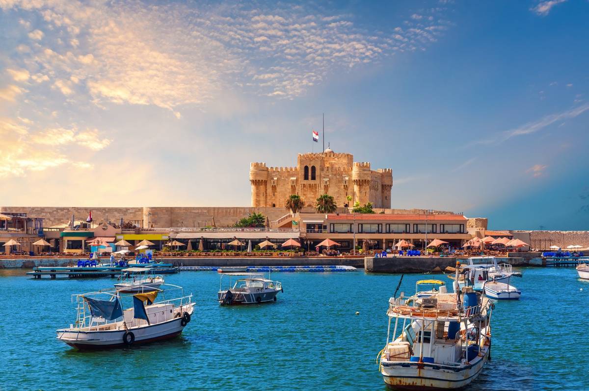 Der Hafen von Alexandria mit der Zitadelle von Qaitbay und fahrenden Schiffen auf tiefblauem Wasser