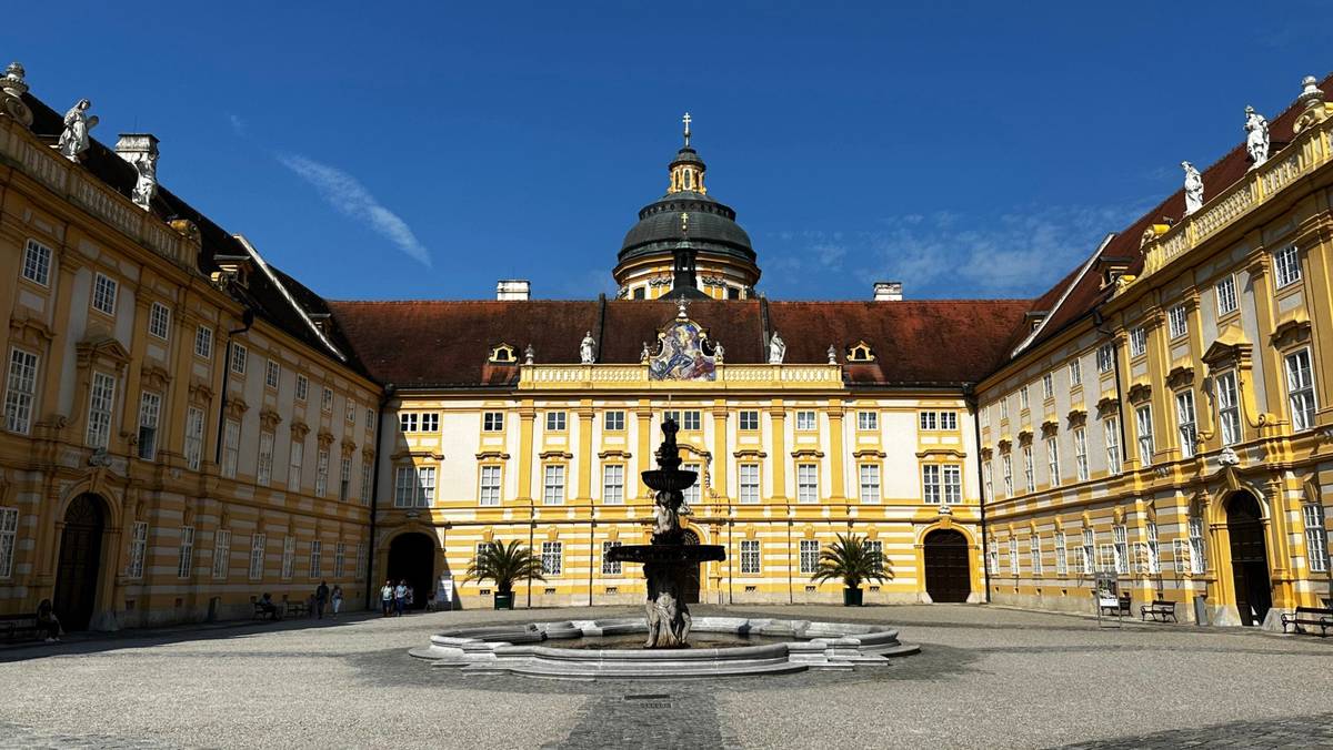 Das Hofgelände von Stift Melk mit Springbrunnen bei klarem Himmel