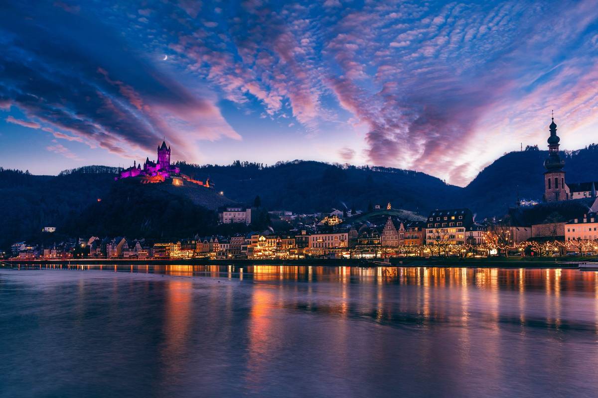 Reichsburg Cochem thront über der Mosel in  neongefärbtem Licht bei Nacht