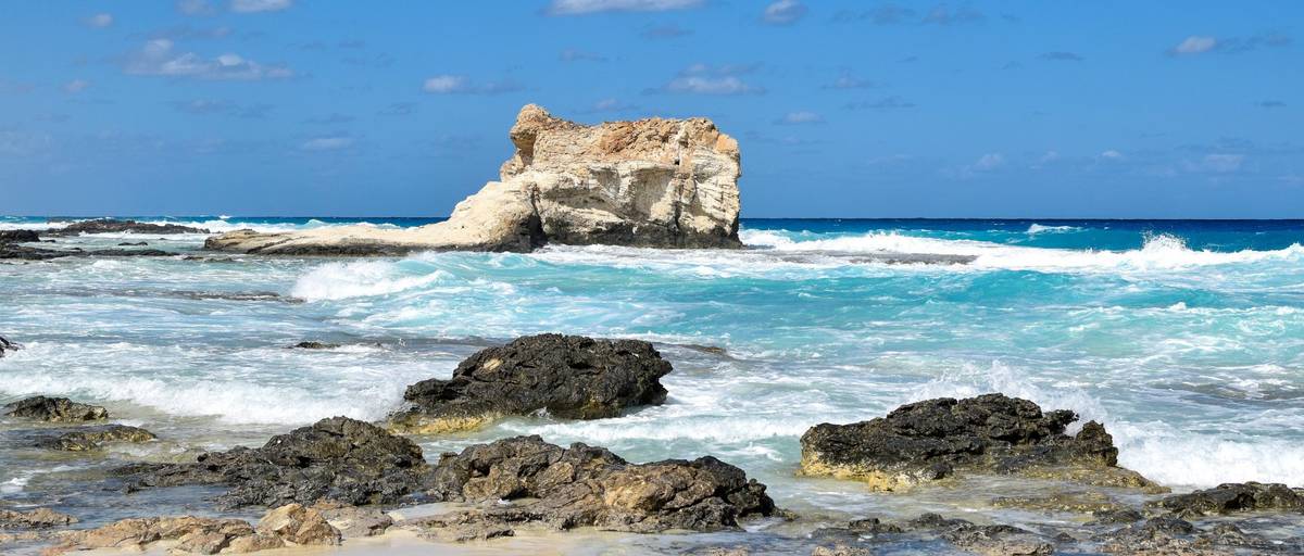 Mediterrane Küste Ägyptens am Kleopatra Strand in der Nähe von Marsa Matruh, Blick auf markanten Felsen inmitten von Wellen