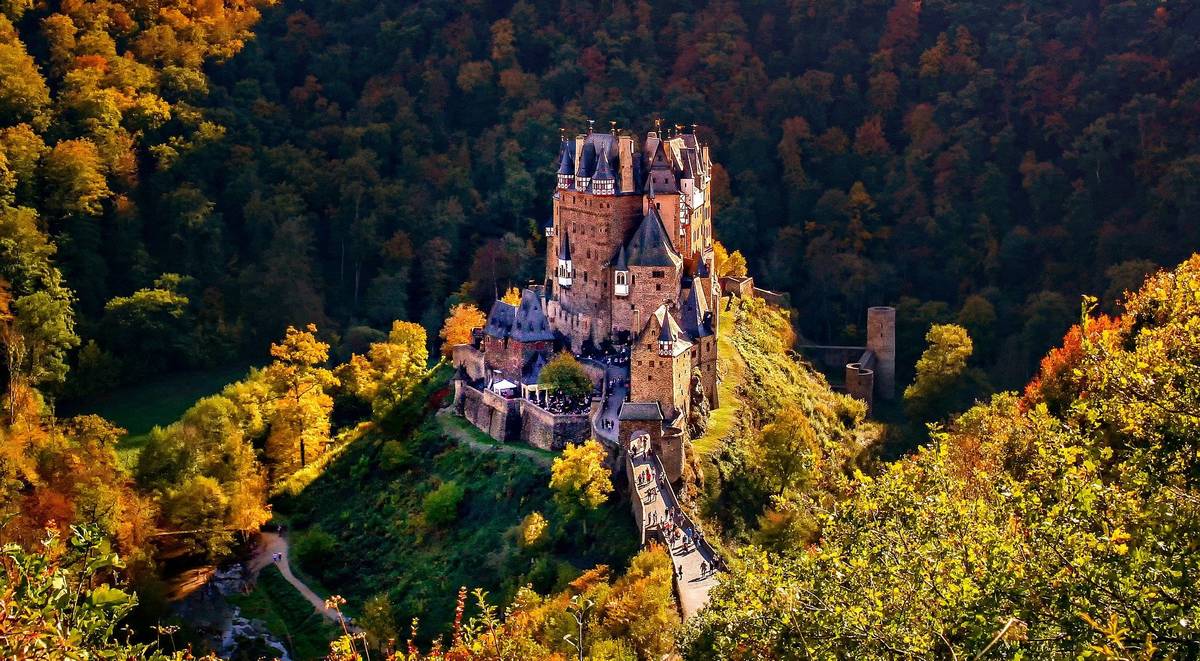 Historische Burg Eltz in der Mitte einer herbstlichen Landschaft mit Bäumen