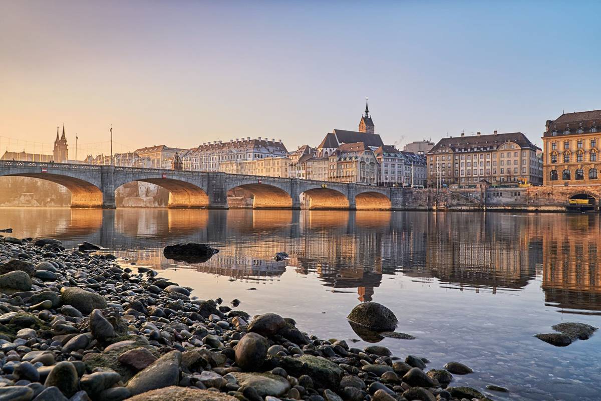 Frühmorgendliches Bild von Basel am Rheinufer mit Brücke