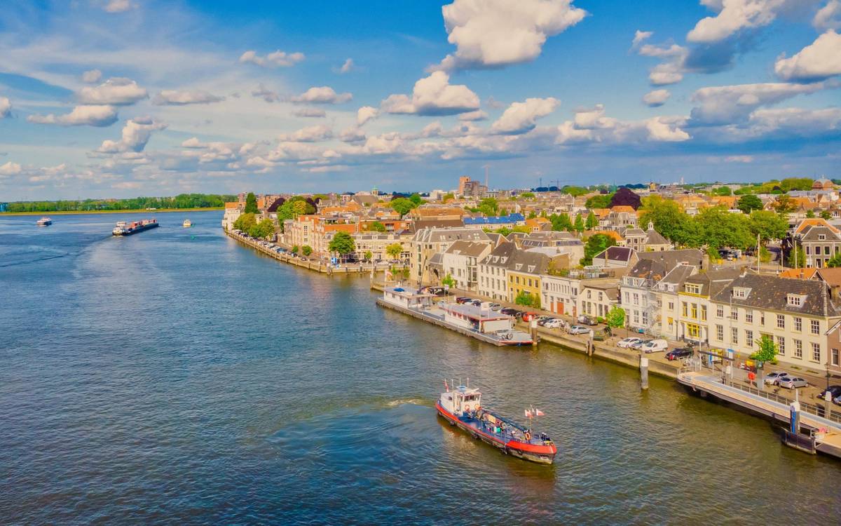 Luftaufnahme von Dordrecht in den Niederlanden am Flussufer des Drei-Flüsse-Eck. Ein Schiff ist auf dem Wasser zu sehen, ebenso die Hafen Skyline Dordrechts.