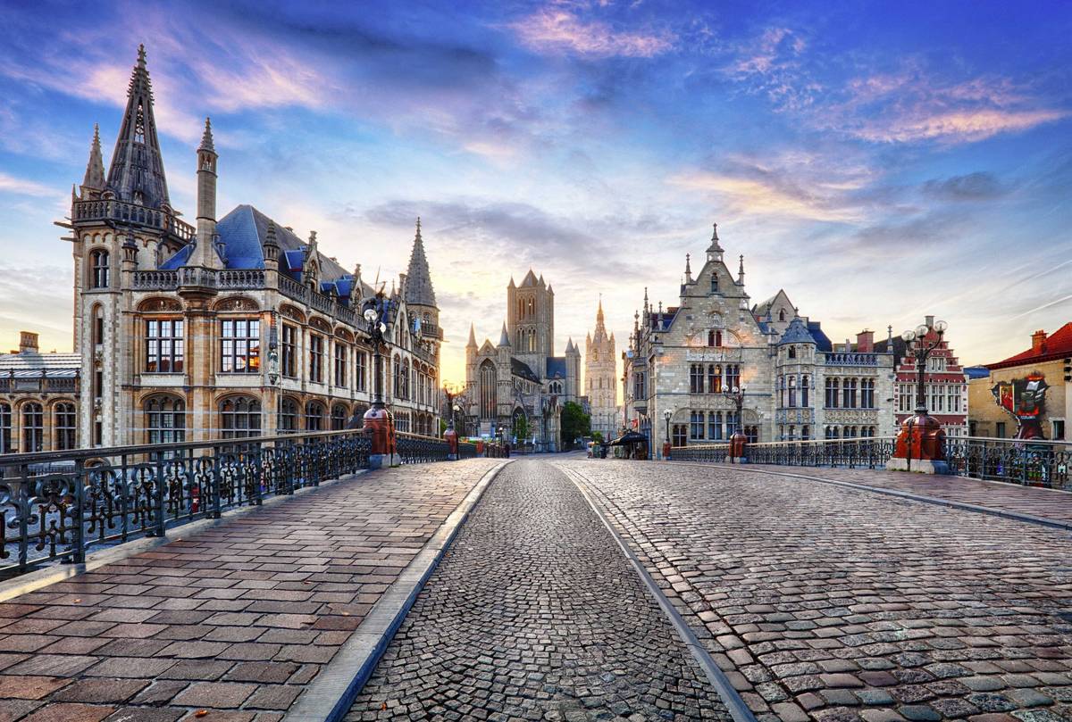 Brückenübergang in der Altstadt vom belgischen Gent mit pink-blauen Wolken auf blauem Himmel
