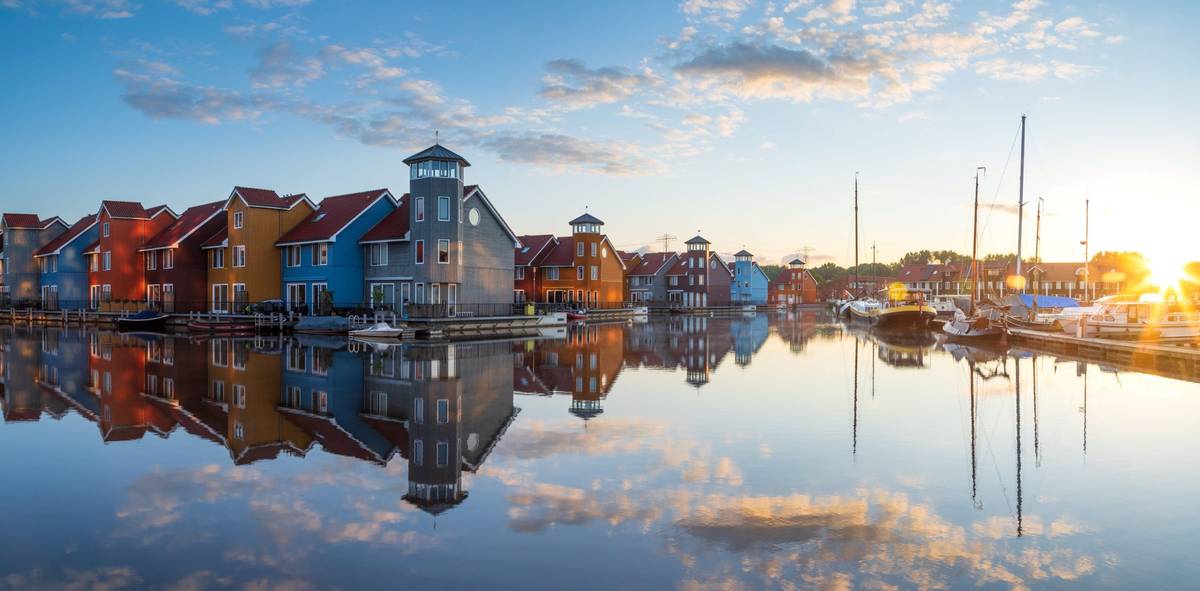 Ansicht auf das niederländische Groningen. Bunte Häuser spiegeln sich nahezu perfekt im Wasser und sorgen damit für ein stimmungsvolles Bild.