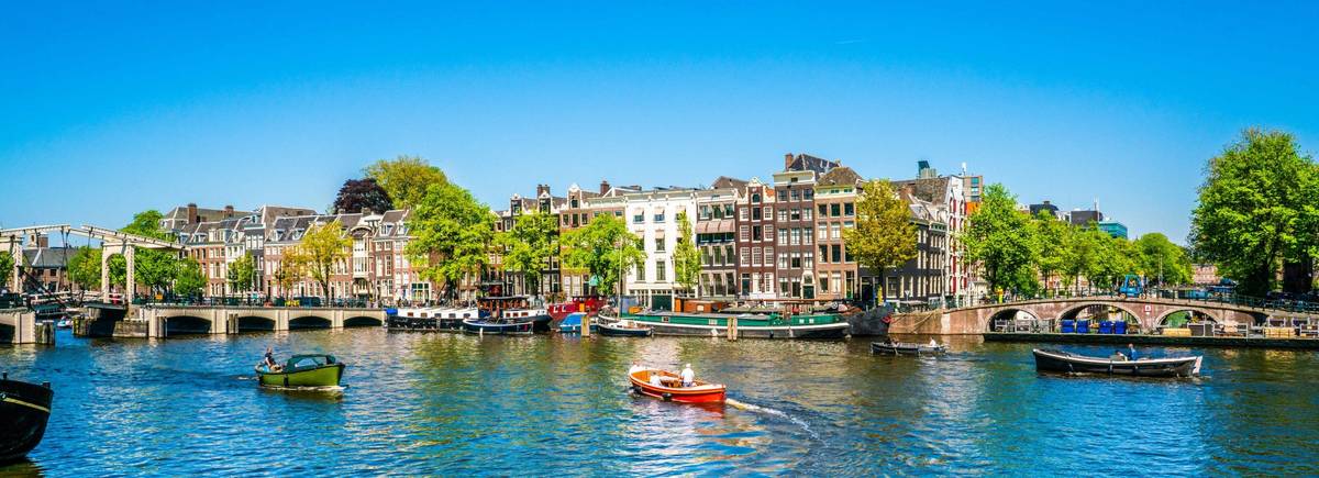 Panoramaaufnahme von Grachten in Amsterdam auf blauem Kanalwasser und rotem Boot in der Mitte