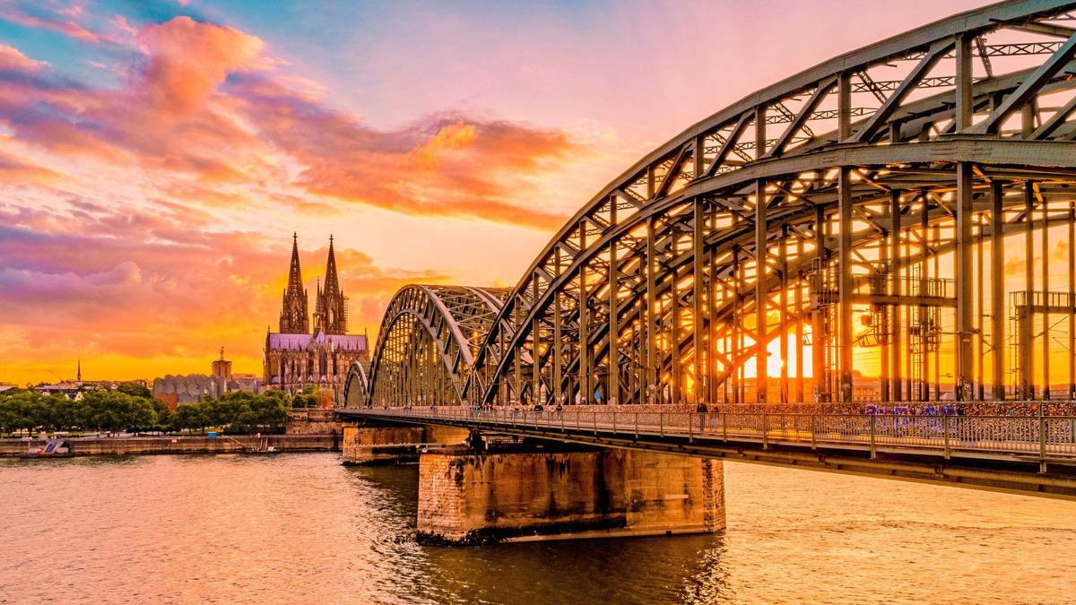Goldenes Abendlicht am Rhein mit Hohenzollernbrücke in Köln mit dem ikonischen Wahrzeichen der Stadt, dem Kölner Dom