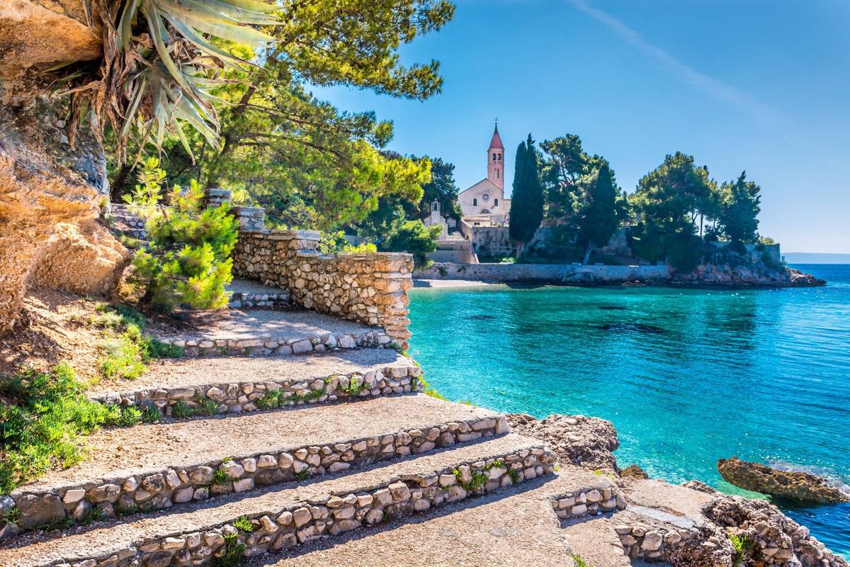 Aufnahme des Dominikanerklosters in der Stadt Bol auf der kroatischen Insel Brac bei strahlendem Sonnenschein inklusive türkisfarbenem Wasser