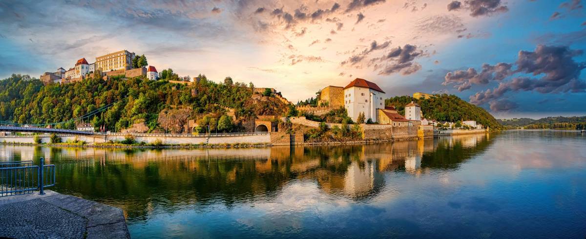 Aufnahme der Burg Veste Oberhaus in Passau an der Donau mit klarer Gegenspiegelung des Panoramas im Wasser bei Sonnenuntergang