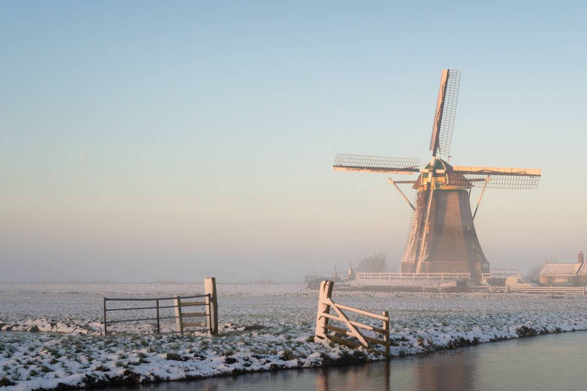 Windmühle im Winter mit Nebel und Schnee am Wasser