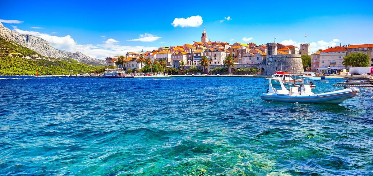 Hafenszene in Korcula in Kroatien bei tiefblauem Wasser mit einzelnem Boot