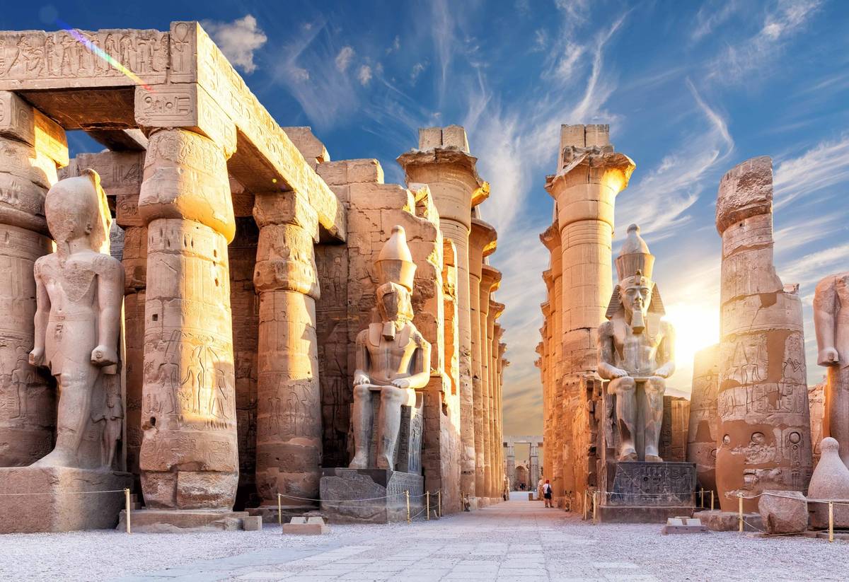 Haupteingang des Luxortempels mit vielen Säulen und Pylonen bei einem hellen Sonnenaufgang