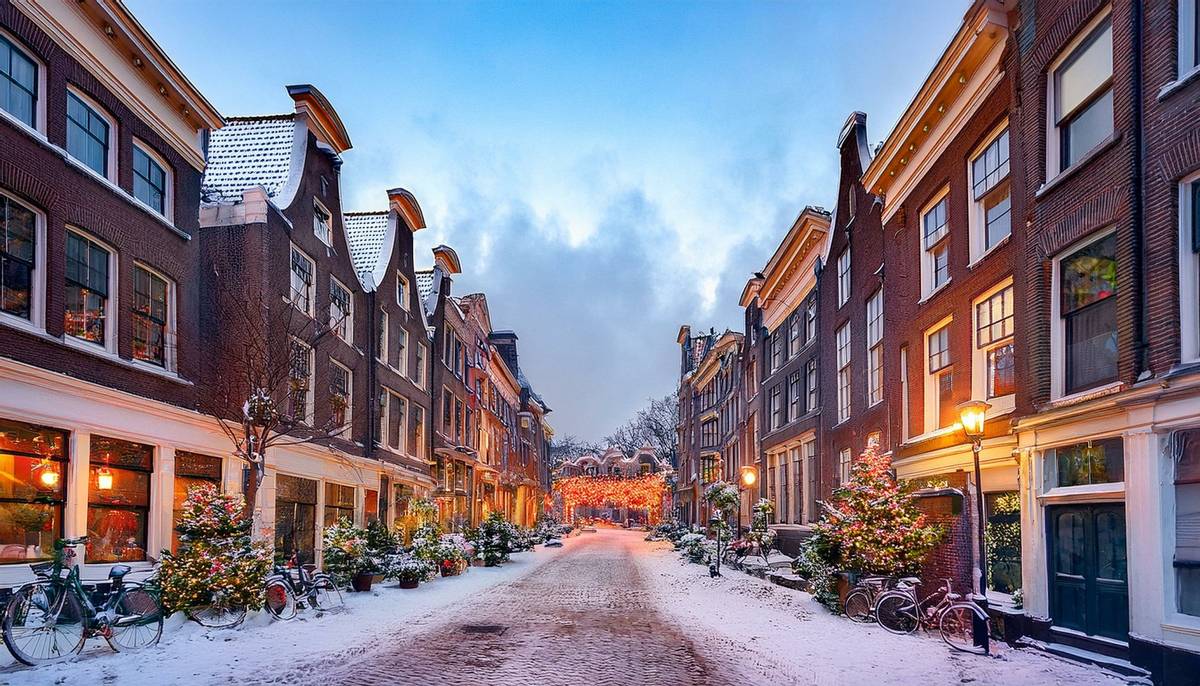 Niederländische Straße im Winter mit Schnee. Die Häuser sind stimmungsvoll beleuchtet, der Himmel eisblau