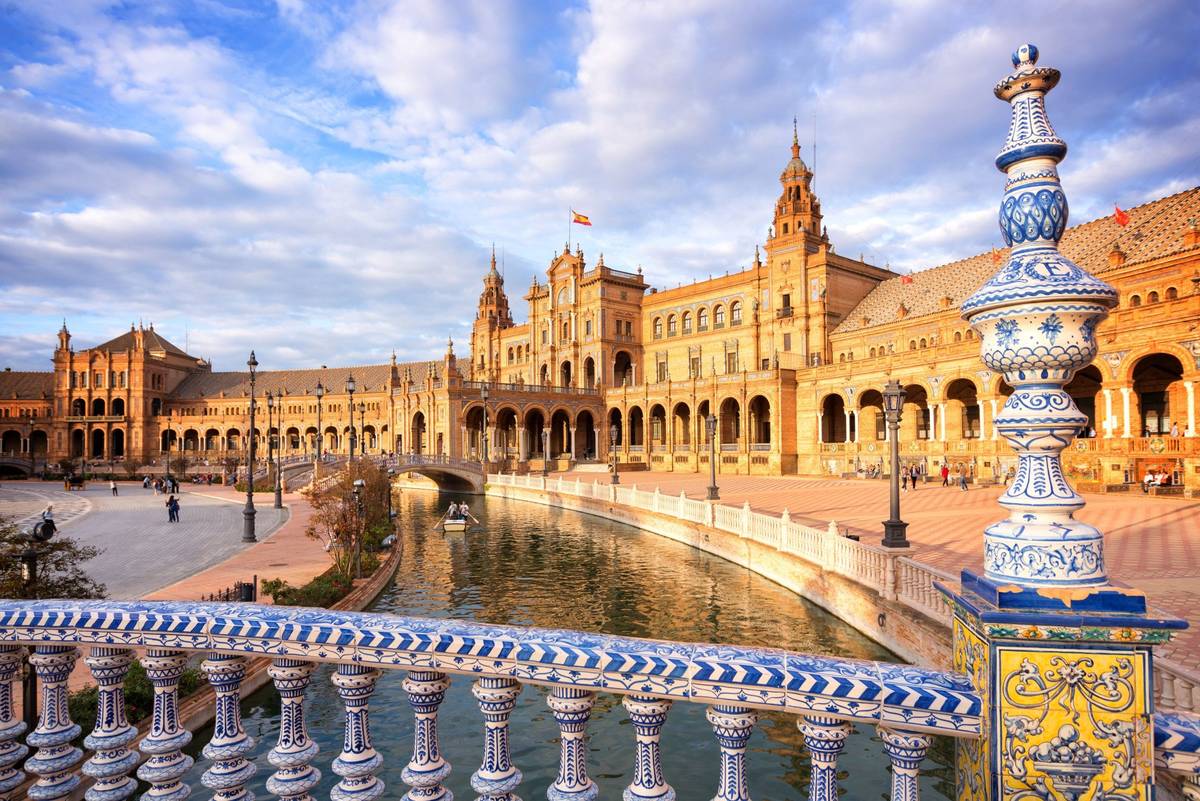 Vordergründig Brücke mit blauem typisch spanischem Azulejos Muster, mit Blick auf den beliebten Plaza de Espana bei Tag