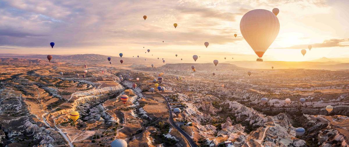 Eine Vielzahl von Heißluftballons fliegen über das Pasabag-Tal im türkische Göreme bei Sonnenuntergang