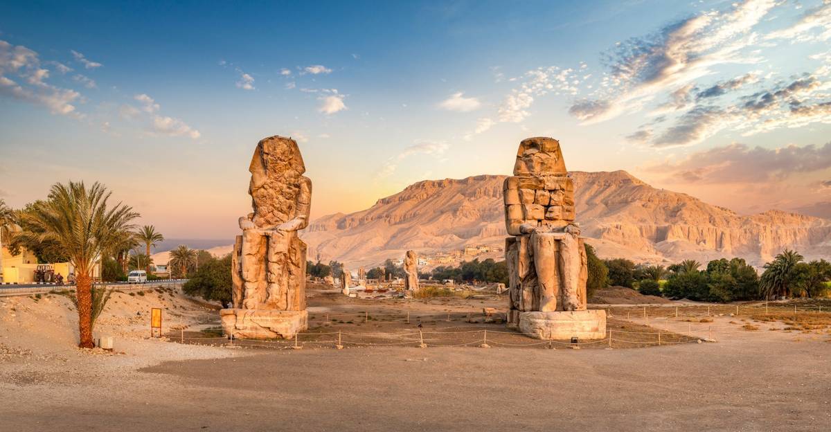 Die bei Touristen beliebten ägyptischen Memnon Kolosse in Luxor bei Sonnenuntergang