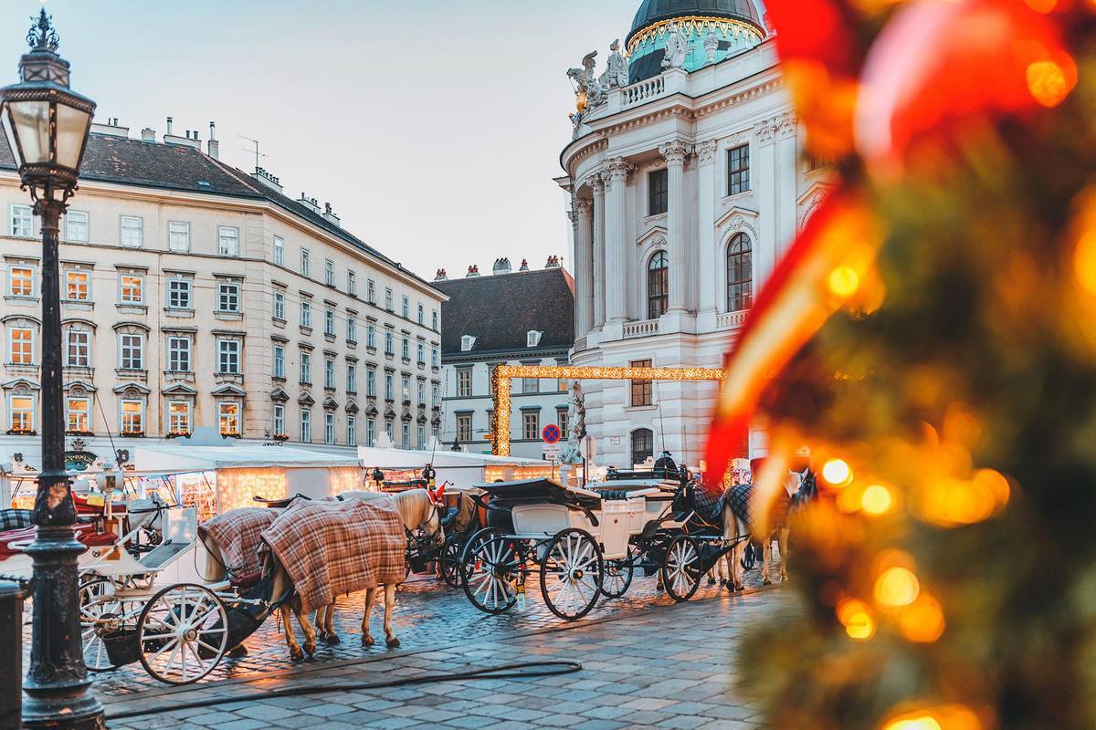 Weihnachtliche Altstadt in Wien mit festlich dekorierten Fassaden. Eine Traditionelle Fiaker Kutsche steht am Rand des Christkindlmarktes.