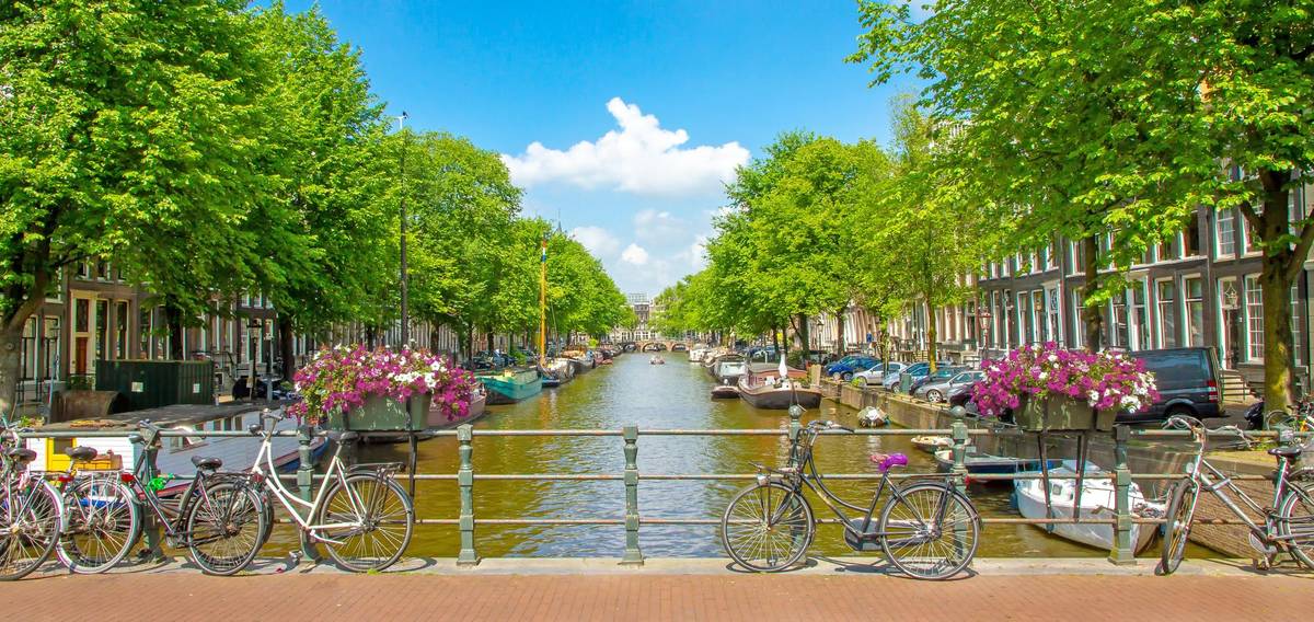 Typisches Bild einer Gracht in Amsterdam bei einer Rheinkreuzfahrt mit Fahrräder und Hausbooten.
