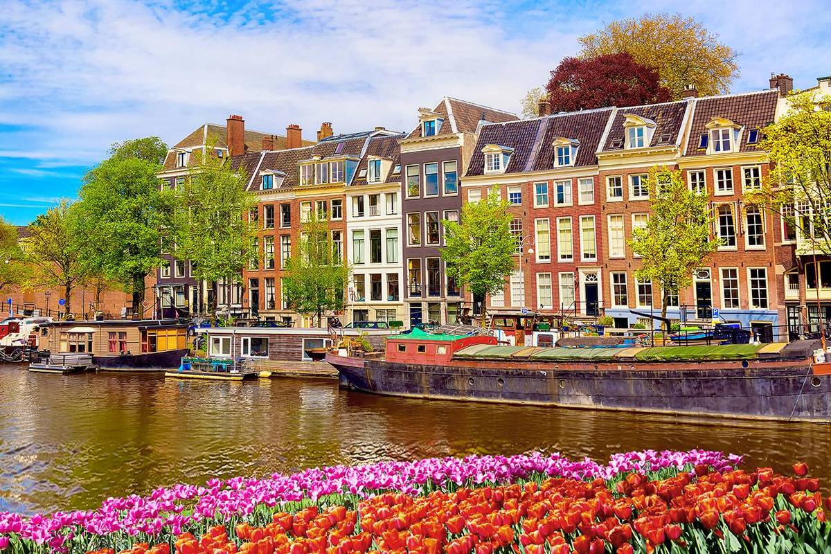 Ausblick auf eine typische Gracht in Amsterdam. Die Grachten repräsentieren das historische Leben in der Altstadt von Amsterdam. Man sieht die klassischen Hausboote die in den Kanälen anlegen.