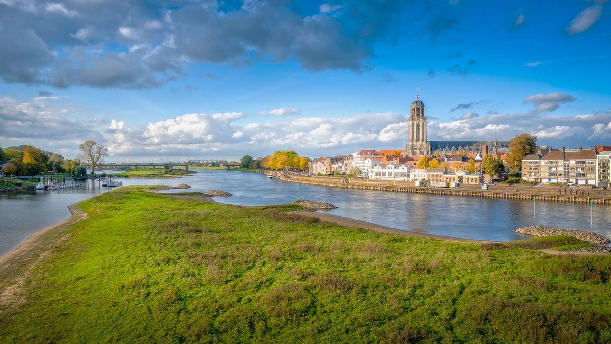 Man sieht das Stadtbild des Hafenstädtchens Deventer in den Niederlanden. Es liegt direkt am Fluss und man sieht die Flusskreuzfahrtanleger.