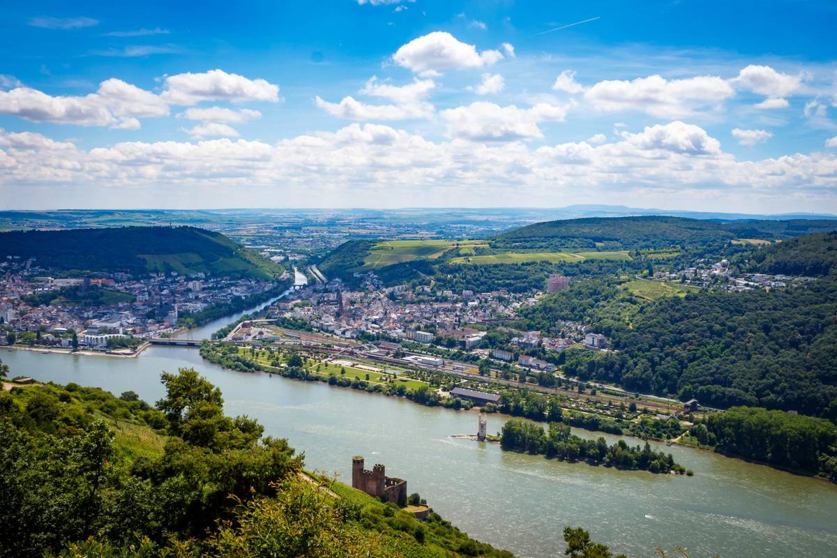 Panorama Ausblick auf die Winzerstadt Rüdesheim. Man sieht das Rheinufer, den Seitenarm des Rheins sowie die Burgruine auf der anderen Flussseite.