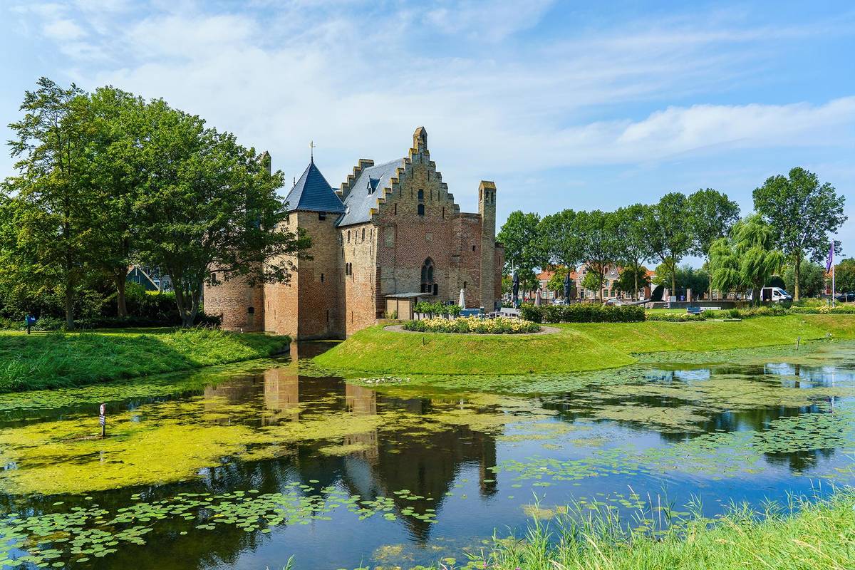 Radboud in Medemblik in Holland. Vor dem Rathaus befindet sich ein kleiner See und die Landschaft ringsum ist saftig grün.