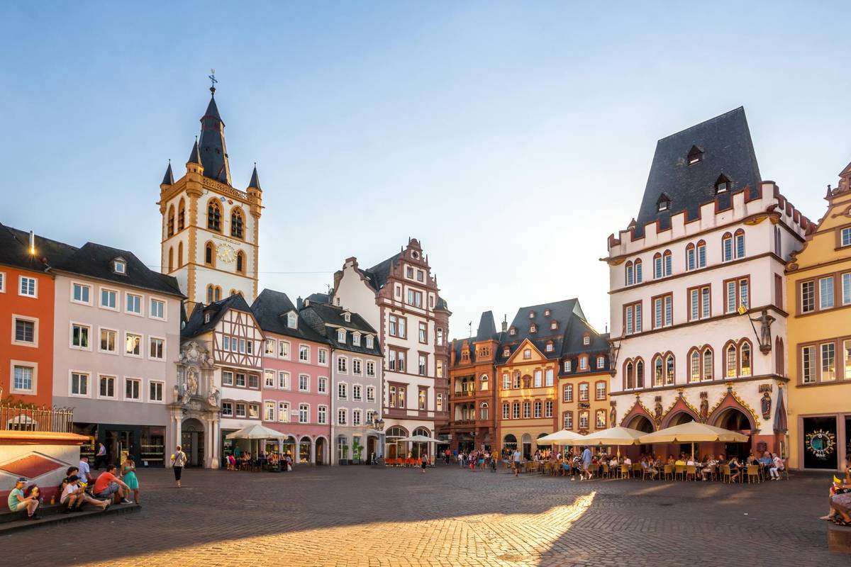 Historischer Marktplatz in Trier, der ältesten Stadt Deutschlands. Die Bars und Cafés sind gut gefüllt und Leute spazieren über dem Platz.