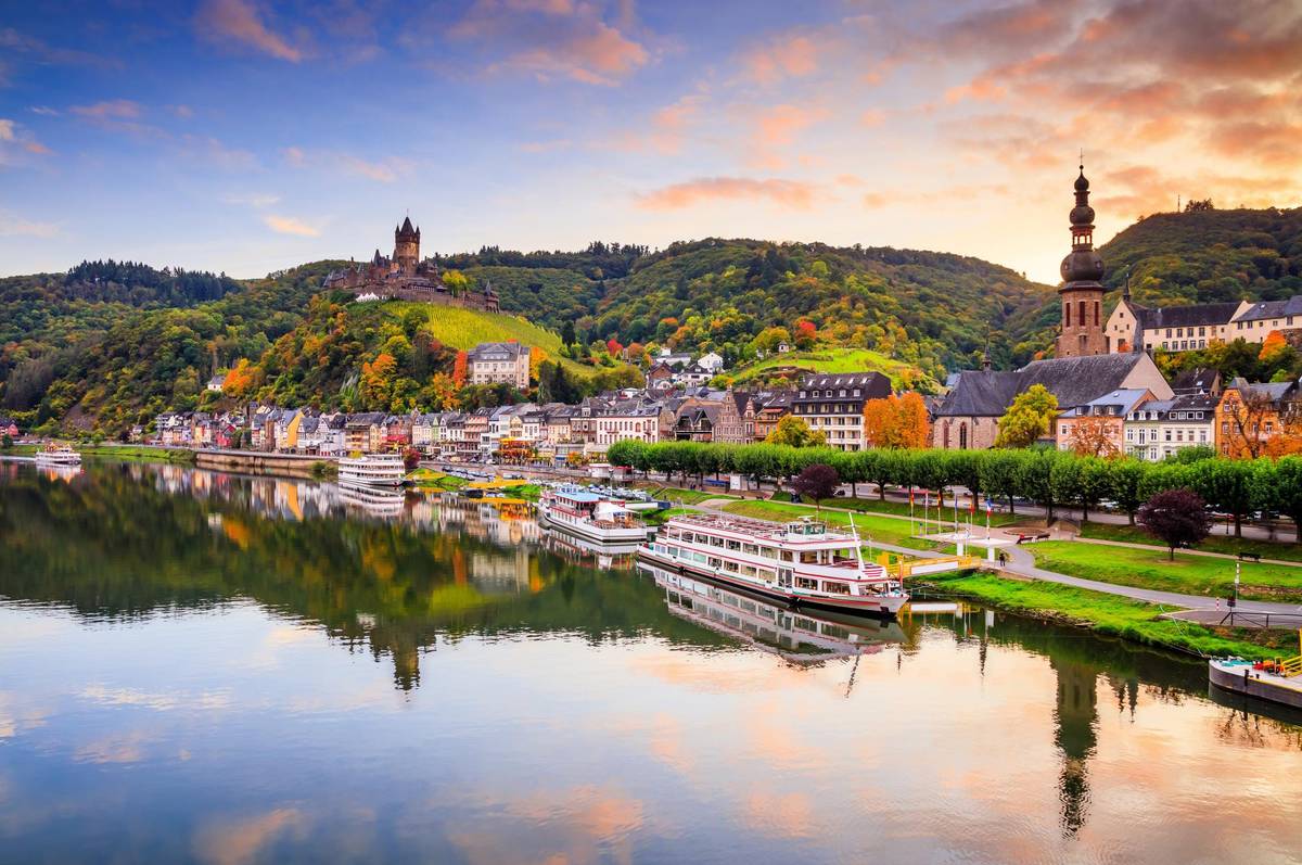 Man sieht das Flusspanorama des Moselstädtchens Cochem. Über dem Dorf thront die alte Reichsburg, das Wahrzeichen der Stadt.