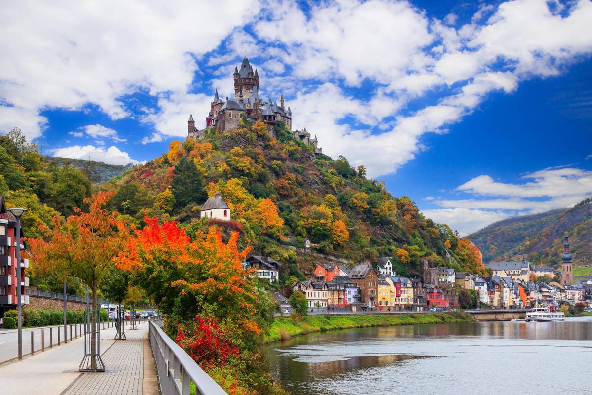 Cochem im Herbst mit der Reichsburg inmitten von bunten Bäumen und Büschen